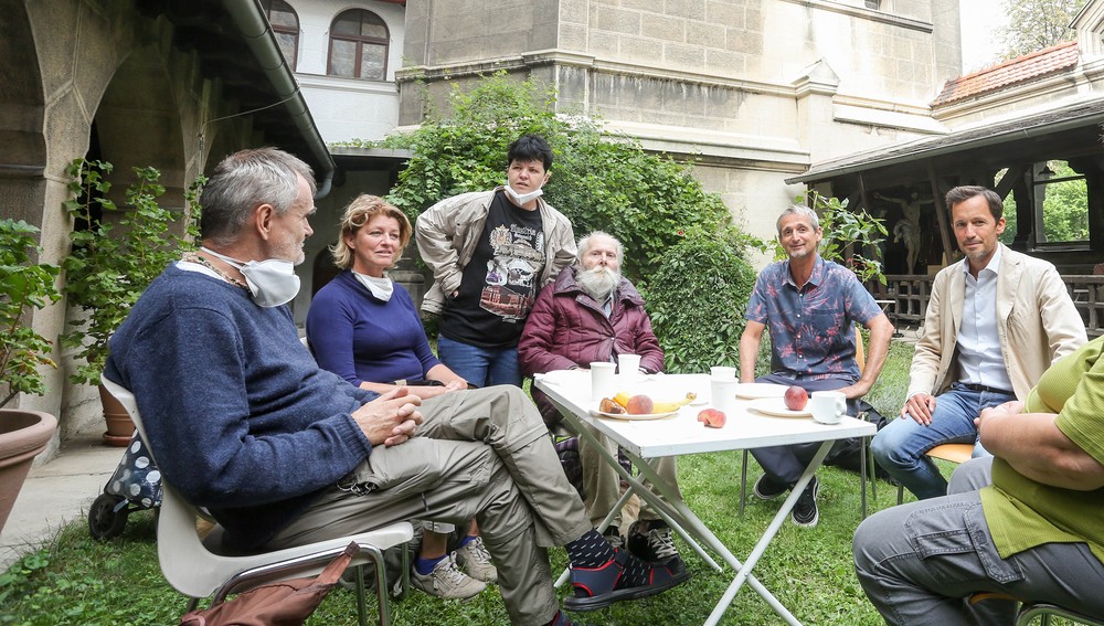 Menschengruppe beim Zusammensitzen im Pfarrgarten Wien Canisius