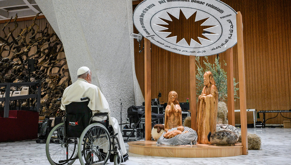 Papst Franziskus betet vor der Krippe am 7. Dezember 2024 in der Audienzhalle im Vatikan. Das Jesuskind liegt auf einem schwarz-weißen Palästinensertuch.