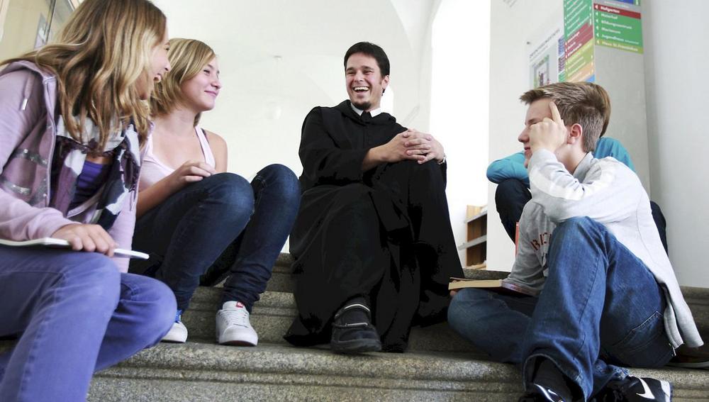 Junger Ordensmann im Gespräch mit Jugendlichen