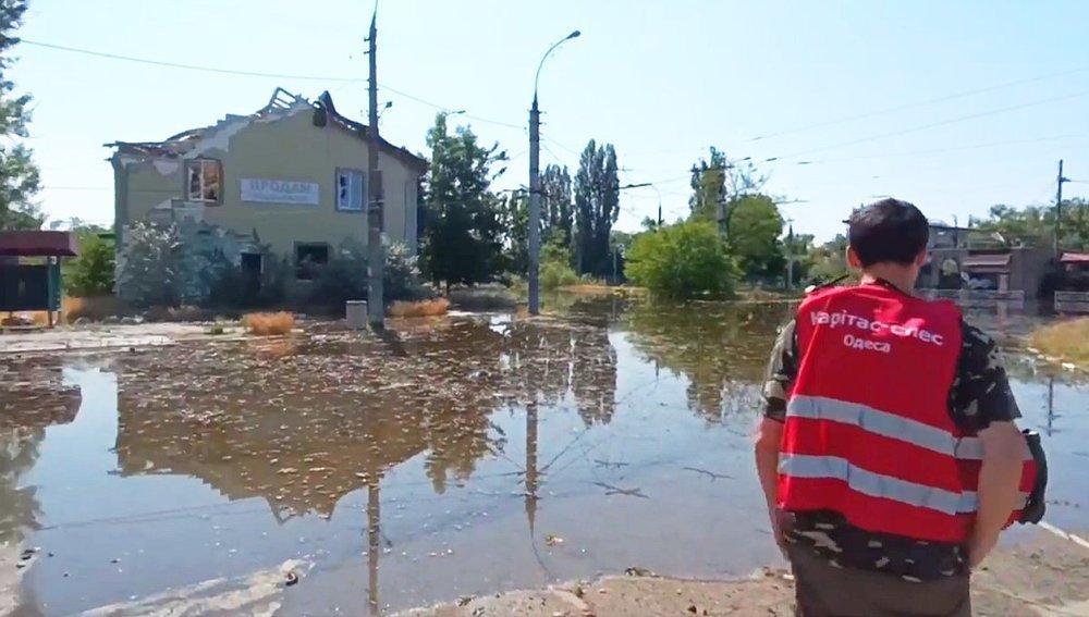 Caritas-Mitarbeiter vor überflutetem Gebiet bei Cherson