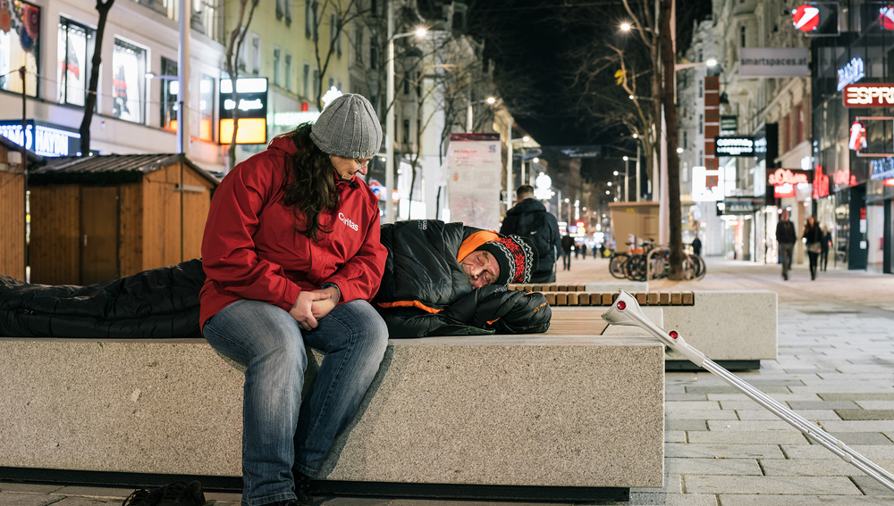 Caritas-Mitarbeiter des Kältebuses hilft Obdachlosem