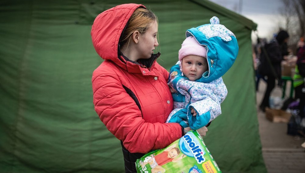 Ukrainische Mutter mit Kind und Windelpackung